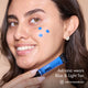 Adriana smiling with HD PRO.Conceal Blue and Light Tan dotted across her face, holding the Blue tube.