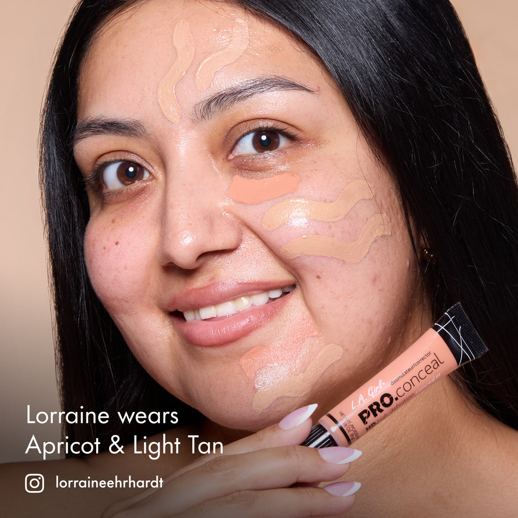 Lorraine smiling with HD PRO.Conceal Apricot and Light Tan striped across her cheek and forehead, holding both tubes.