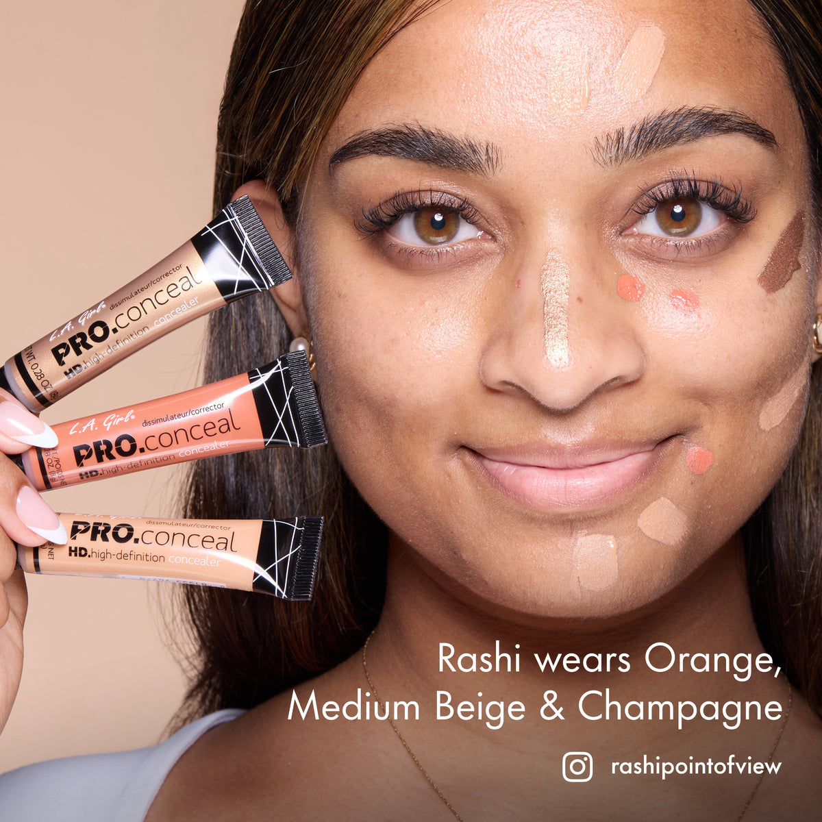 Rashi with HD PRO.Conceal Orange, Medium Beige and Champagne applied to her cheek and forehead, holding three tubes.