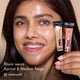 Bhumi with HD PRO.Conceal Apricot and Medium Beige striped across her cheek, holding both tubes.