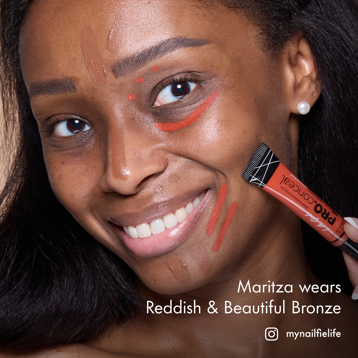 Maritza smiling with HD PRO.Conceal Reddish and Beautiful Bronze applied around her eyes and cheek, holding a tube.
