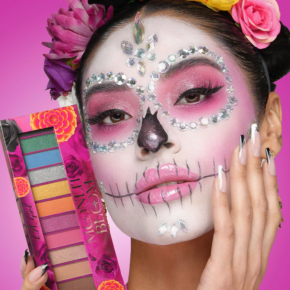 Model in Moonlit Bloom sugar-skull makeup holding the Moonlit Bloom Eyeshadow Palette