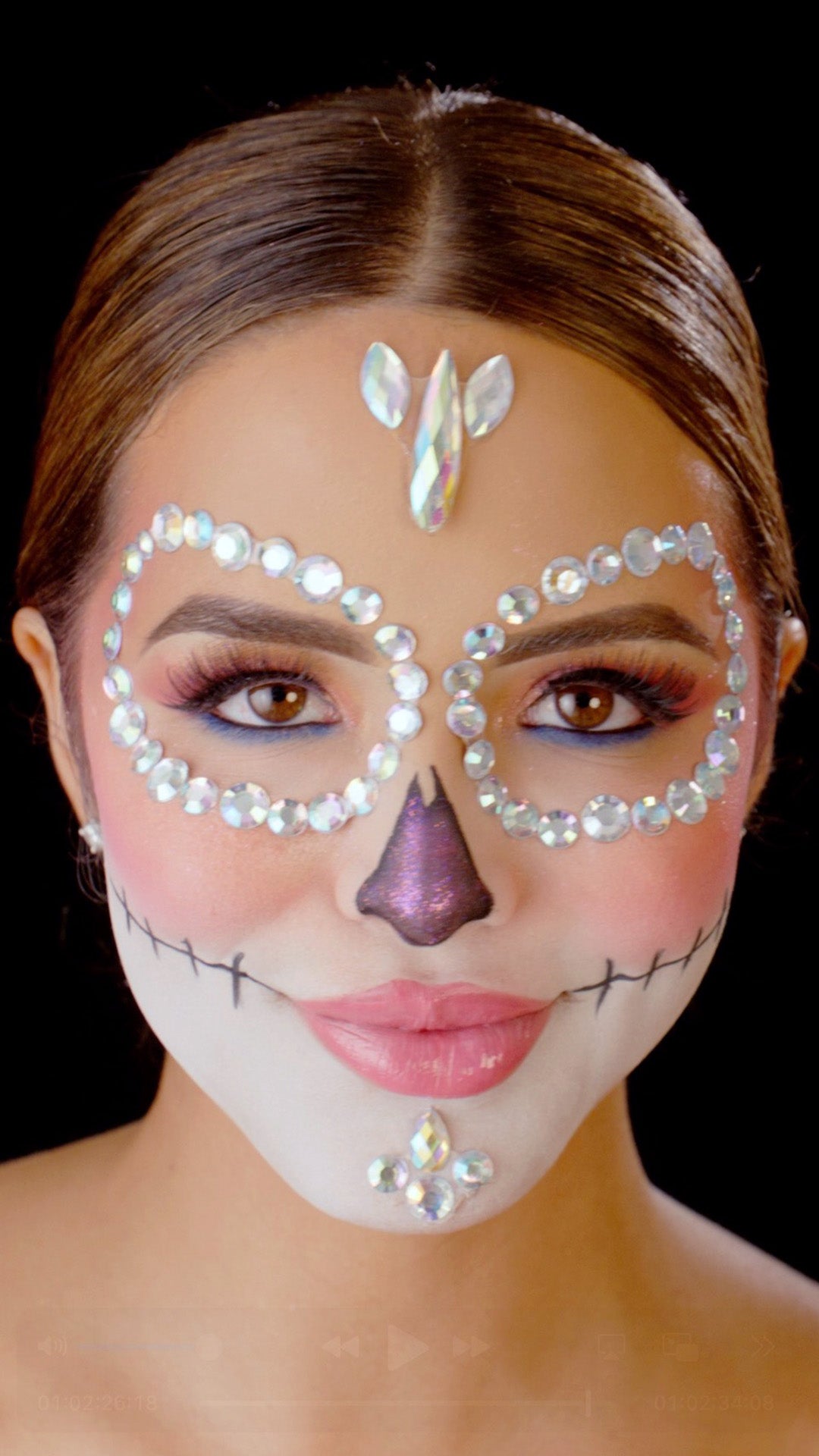 L.A. Girl Moonlit Bloom Face Gems look thumbnail: model with silver jeweled sugar-skull eye masks and pink glitter nose