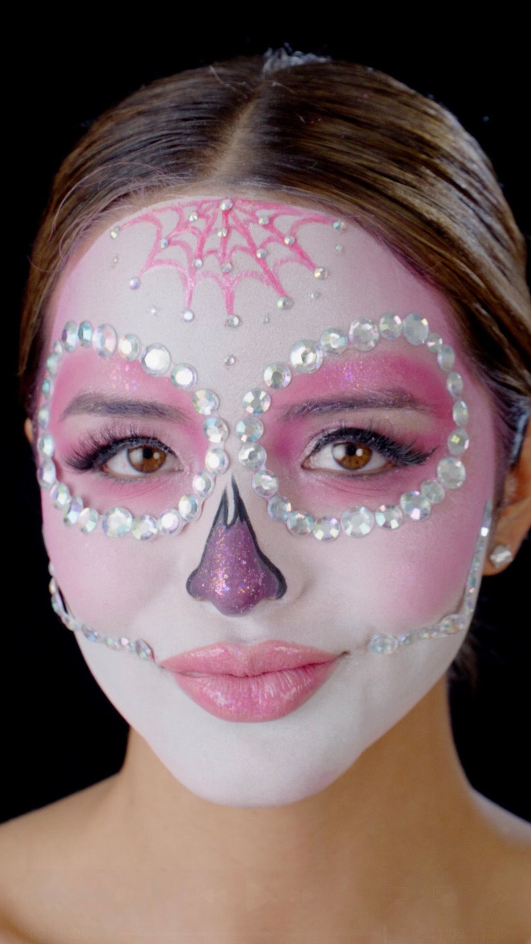 L.A. Girl Moonlit Bloom Face Gems look thumbnail: model with pink jeweled sugar-skull eye masks and a spiderweb forehead design